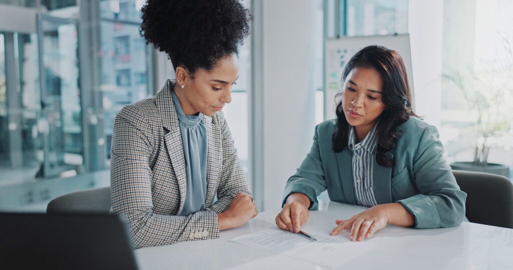 Two professionals reviewing financial documents and taking notes during a mortgage consultation.
