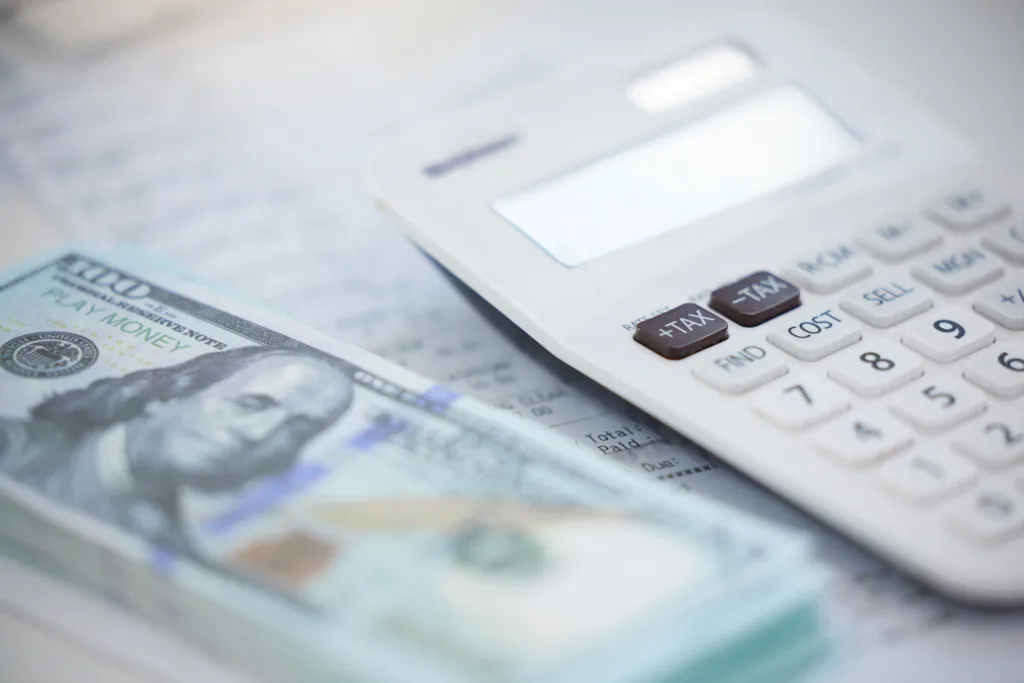 Close up of a calculator resting on US hundred dollar bills.